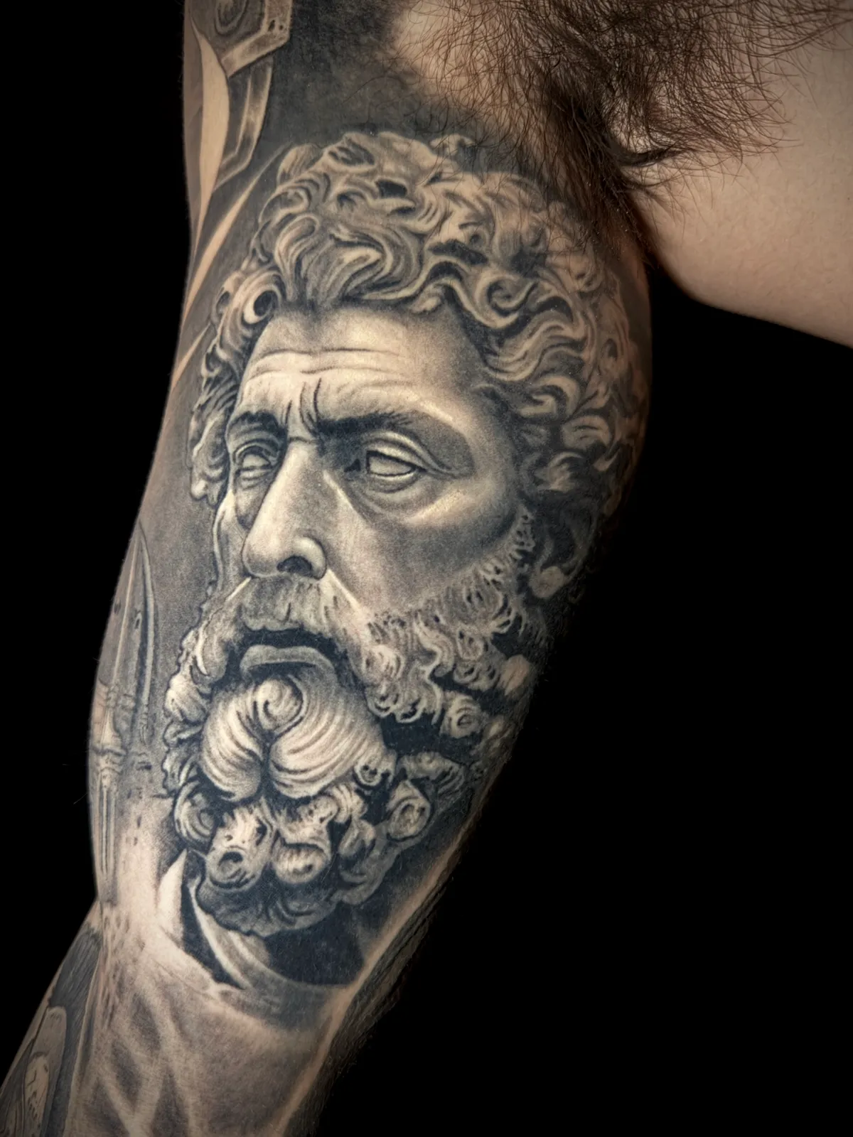 Black and grey hyper realistic Greek philosopher marble bust portrait upper arm tattoo by Andras Tattoo