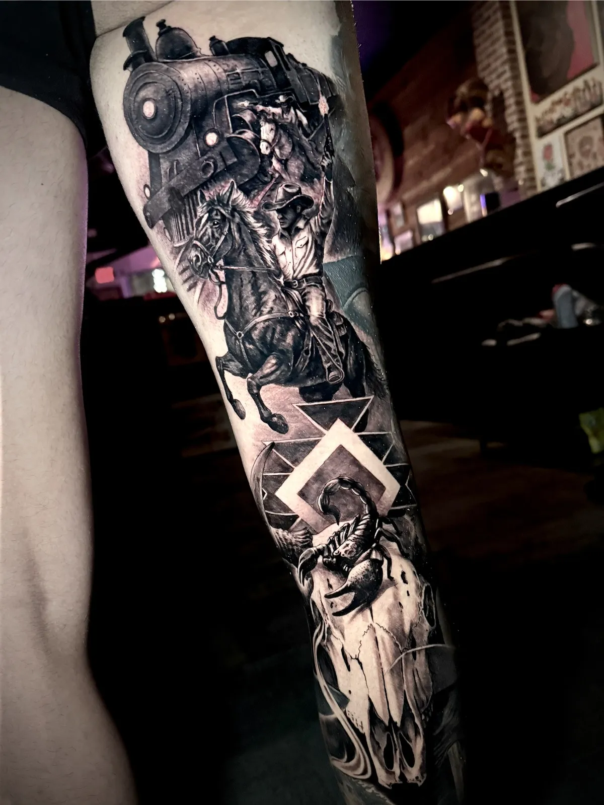 Black and grey realism Western cowboy full sleeve tattoo with train and bull skull by Andras Tattoo